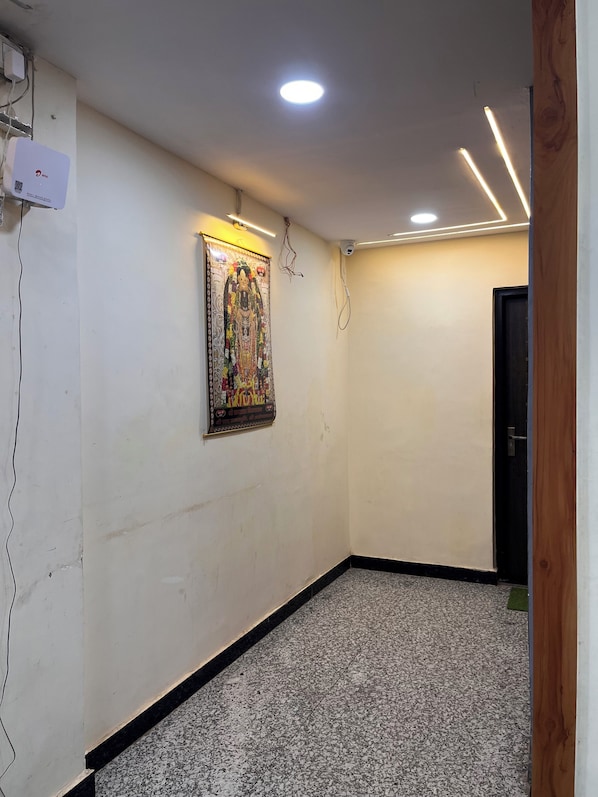 A hallway with a tiled floor, a wall-mounted air conditioning unit, and a door at the end. - Sargam Palace (Varanasi)