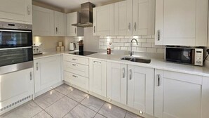 Eine moderne Küche mit weißen Schränken, einem eingebauten Backofen, einer Mikrowelle und einer Edelstahl-Dunstabzugshaube.
