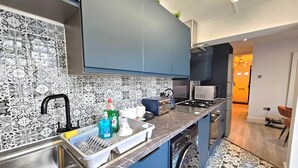 Eine moderne Küche mit dunkelblauen Schränken, einer gemusterten Spritzschutze und einer Edelstahl-Spüle.