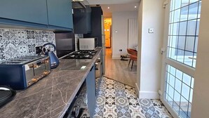 Eine moderne Küche mit dunkelblauen Schränken, einem Gasherd und einer gemusterten Spritzschutzwand.