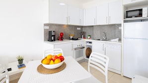 Una cocina moderna con armarios blancos, un microondas, una cafetera y un lavavajillas.