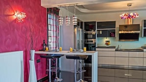 Una cocina moderna con una isla central, taburetes de bar e iluminación colgante.