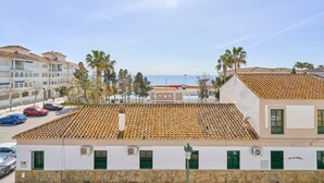 A coastal building with a tiled roof, green shutters, and a view of the sea.