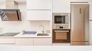 A modern kitchen with a built-in oven, microwave, and stainless steel refrigerator.
