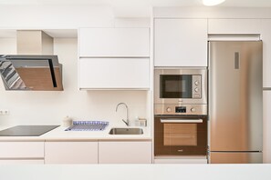 Una cuina moderna amb forn integrat, microones i nevera d'acer inoxidable.
