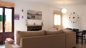 Un soggiorno con un divano color beige, un camino, una sveglia e un'area pranzo con sedie e un tavolo.