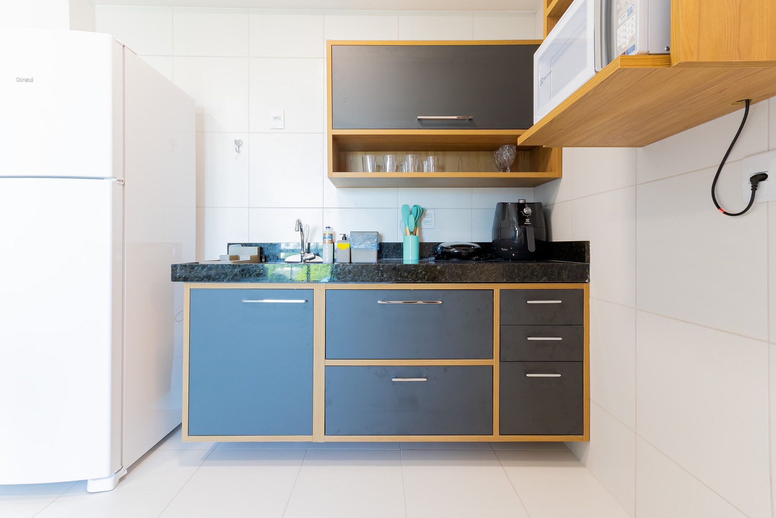 A kitchen with a refrigerator, microwave, and coffee maker on the countertop.