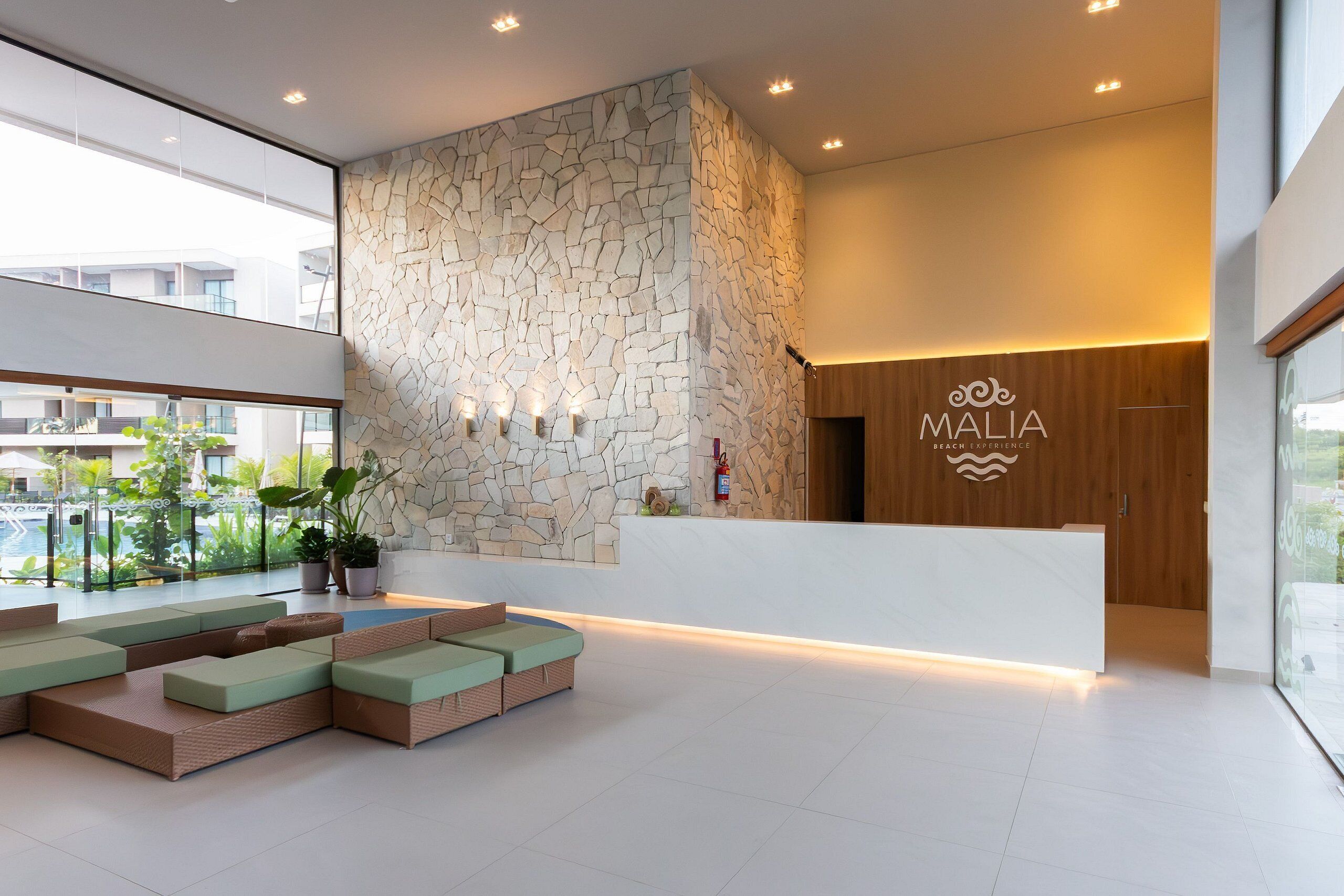 Uma área de recepção moderna com parede de pedra, balcão de madeira e espaço de estar com almofadas.
