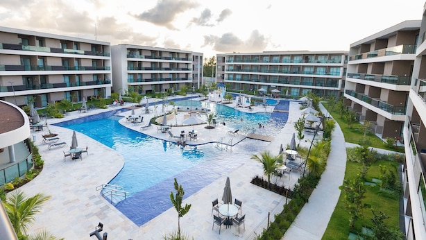 Un resort con piscina central, varios balcones y zonas de estar al aire libre.