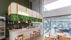 Zona de bar moderna con un letrero que dice 'drinks', taburetes de madera y vista a la piscina.