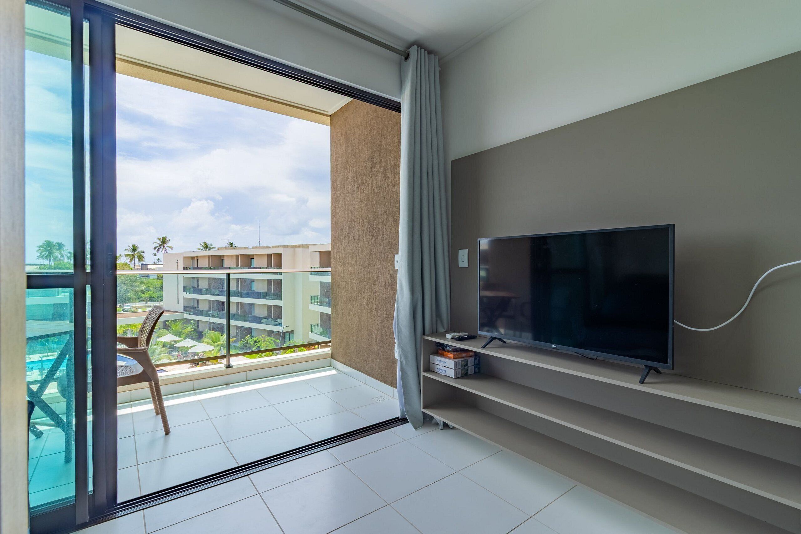 Habitación de hotel moderna con balcón, televisor de pantalla plana y vista a una zona residencial.