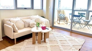 Un salon comprenant un canapé, une table basse et une vue sur un espace extérieur aménagé, accessible par une porte vitrée.