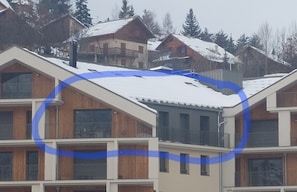 Ein mehrstöckiges Gebäude mit Balkonen und einem mit Schnee bedeckten Dach.