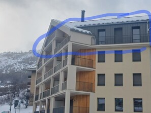 A multi-story building with balconies, a chimney, and a snowy landscape in the background. - Cimes A401 by Avecoeur (Briançon)