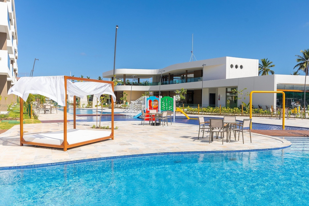 A swimming pool area with a white canopy, lounge chairs, and a children's play area.