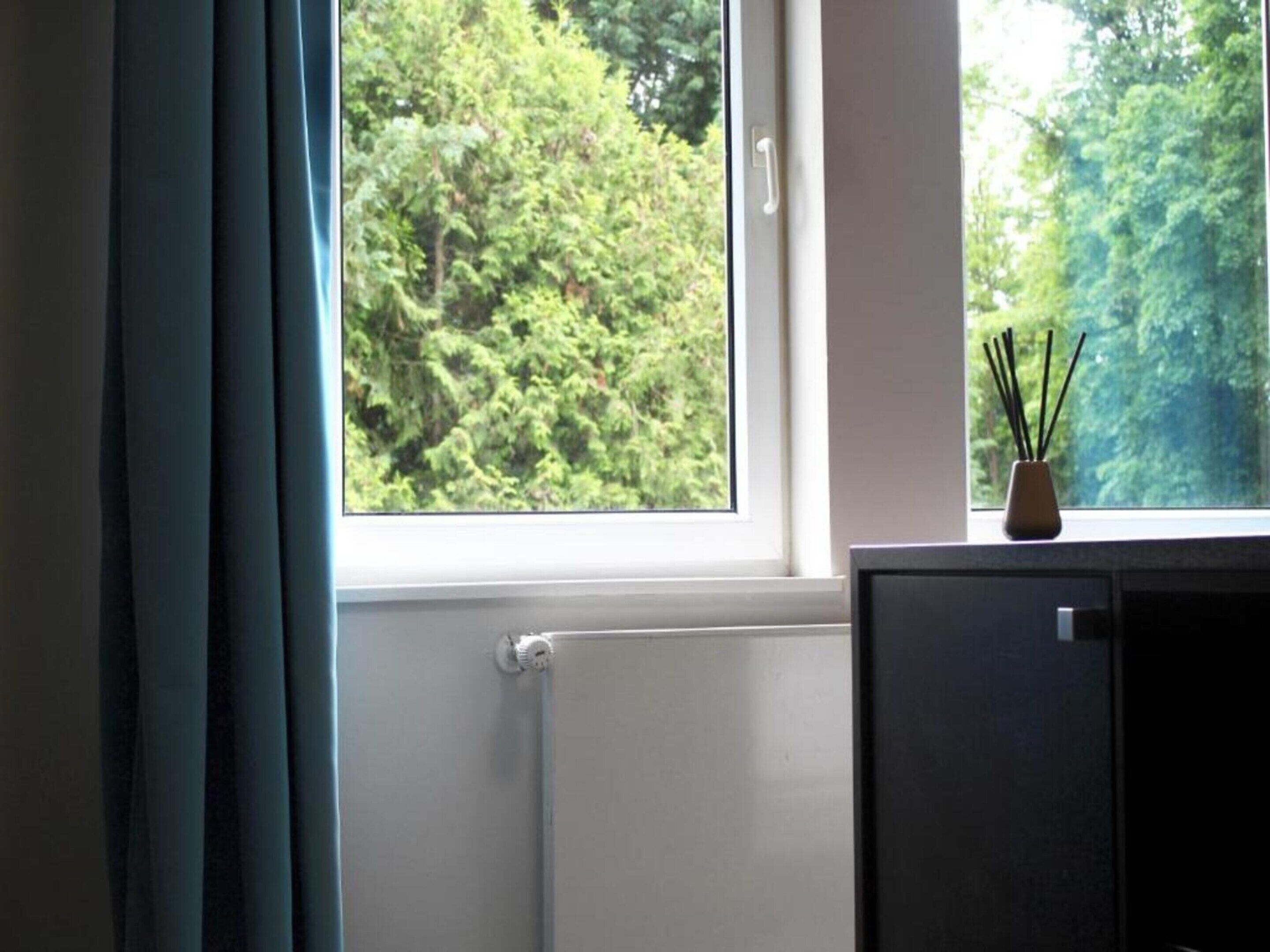A room with a window, a radiator, and a small cabinet with a decorative item on top.