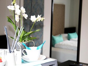 A hotel room with a bed, a mirror, a white orchid plant, and a cup with a napkin. - Koblenz Valley Hotel Double Room Extra Bed (Bendorf)