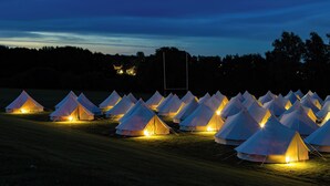 Un champ rempli de tentes illuminées, disposées en rangées.