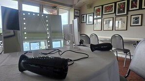 Une pièce comprenant une table, un sèche-cheveux, un miroir avec éclairage, des tableaux encadrés accrochés au mur et une fenêtre.