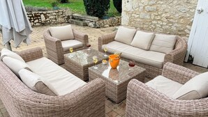 A wicker outdoor seating area with a stone wall and a clock. - Dordogne Maison & Gîte with Pool, Gardens and Terraces Near Bergerac (Pomport)