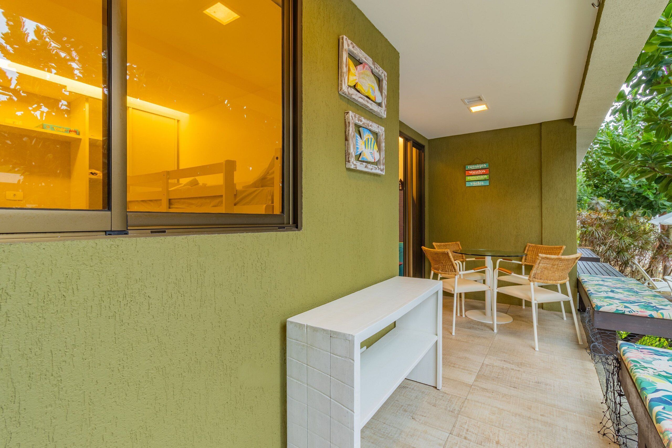 Una habitación con un ventanal grande, un banco blanco y una mesa con sillas.