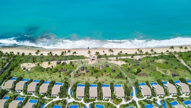 An aerial view of a resort with multiple bungalow-style accommodations, a beach, and a pool area. - Malawi #104a - Seaside Apartment by Carpediem (Ipojuca)