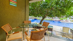 A glass table with wicker chairs, a sign with words, and a view of a swimming pool. - Malawi #104a - Seaside Apartment by Carpediem (Ipojuca)
