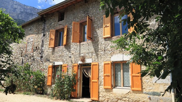 A stone building with wooden shutters, a satellite dish, and a door. - Gite du Souillet à la Ferme (Noyarey)