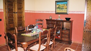 Un comedor con una mesa de madera, sillas, un aparador y un cuadro en la pared.