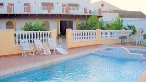Una piscina con sillas de descanso y una pequeña terraza.