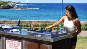 A person at a counter with a sign instructing not to use the cooktop.