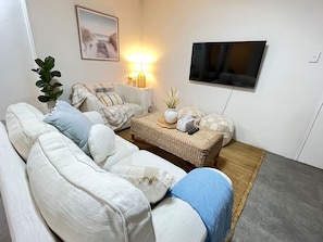 Un salon avec un canapé, une table basse, un téléviseur et une lampe.