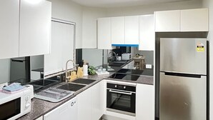 A modern kitchen with white cabinets, stainless steel appliances, and a black countertop.