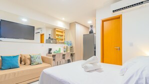 Et moderne hotelværelse med seng, sofa, skrivebord og fjernsyn.