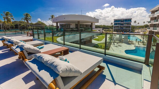A rooftop pool area with lounge chairs and a view of the pool and surrounding buildings. - Makia Beach #b308 - em Muro Alto por Carpediem (Ipojuca)