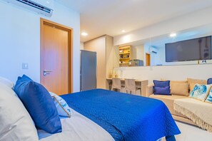 Ein Hotelzimmer mit einem Bett, einer Couch, einem Schreibtisch, einem Fernseher und einer Küchenzeile.