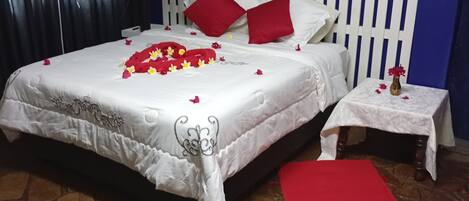 A bedroom with a bed, a nightstand, a red runner, a white canopy, a blue wall, a white picket fence, and a painting of a cow.