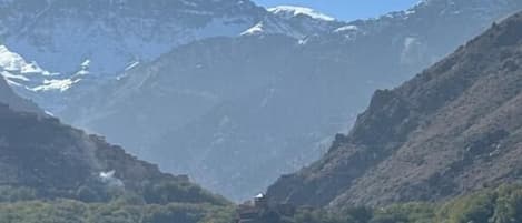 Un paisaje montañoso con un valle y un pequeño edificio ubicado entre árboles.