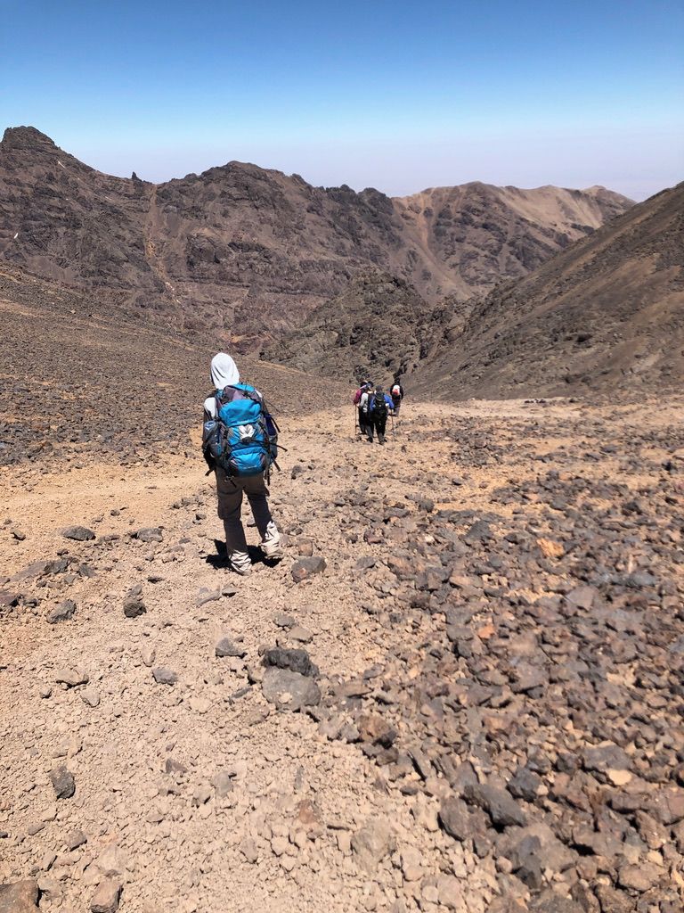 A rocky hiking trail with hikers in the distance.