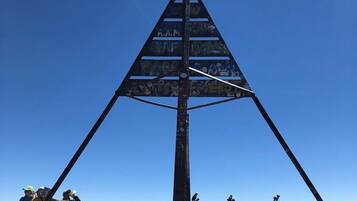 A large metal structure resembling a pyramid with graffiti on its surface, set on rocky terrain.