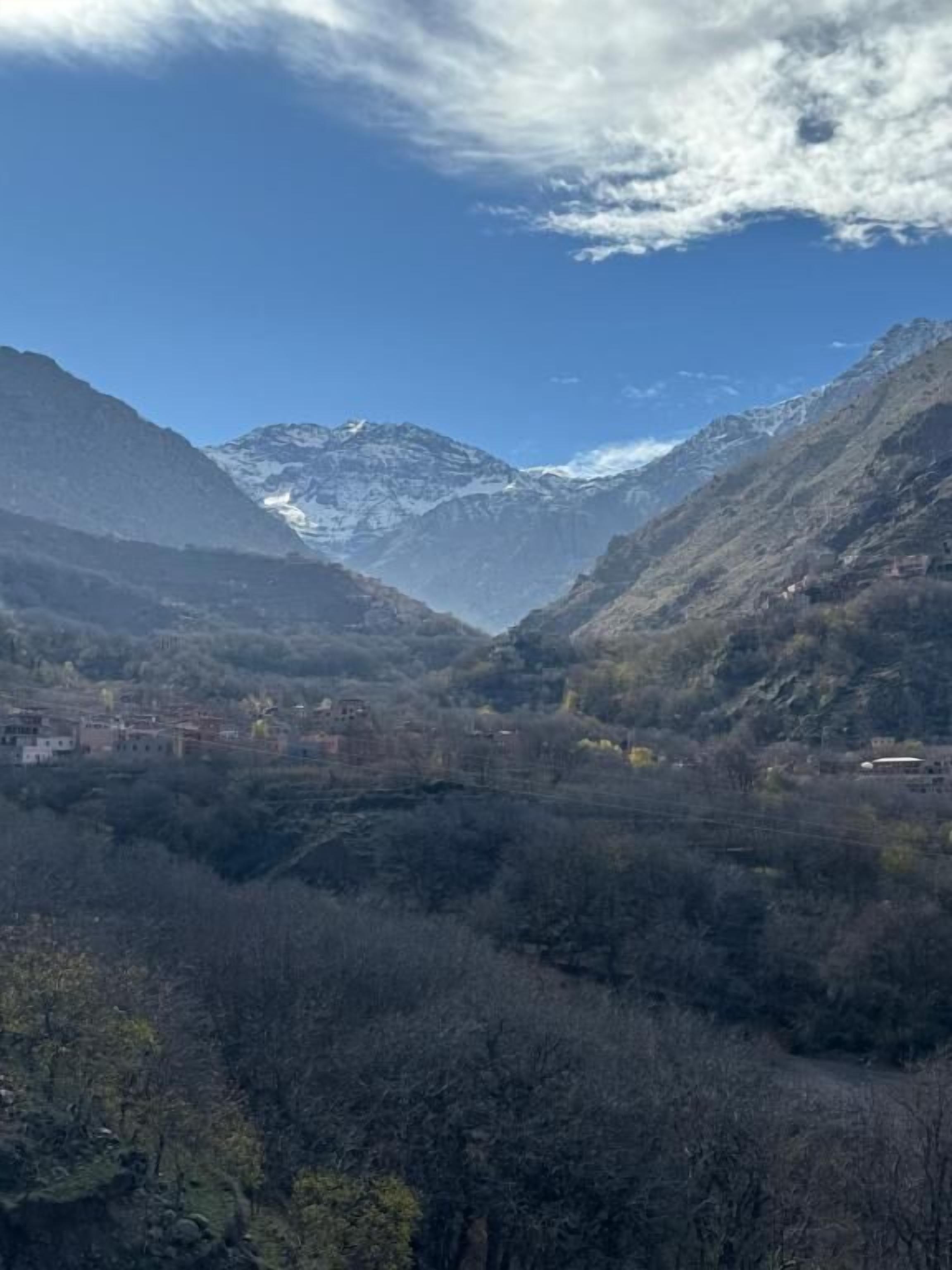 A mountainous landscape with a valley, buildings, and a clear sky.
