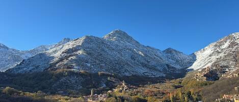 A mountainous landscape with snow-covered peaks and a valley with buildings.