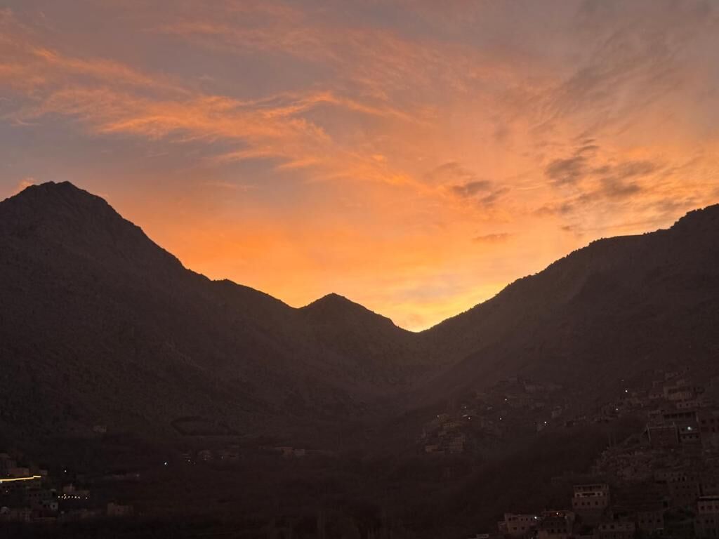 A mountainous landscape with a valley and a sunset.