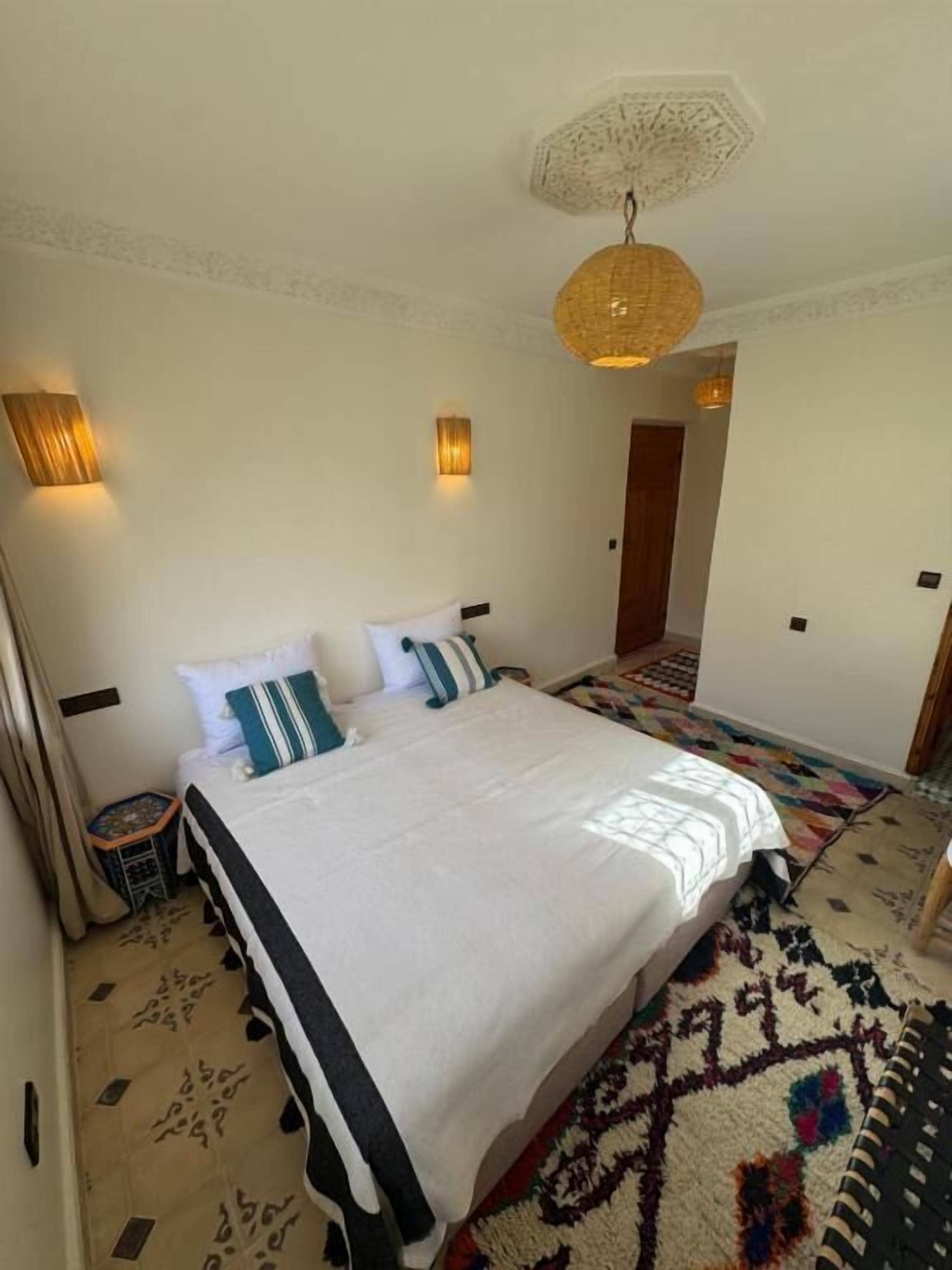 A neatly arranged bedroom with a large bed, two bedside lamps, and a patterned rug.