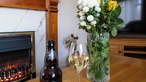 A bottle of Northern Light Blonde Ale, a glass of white wine, and a vase with flowers on a wooden table. - Havrock with harbour view near town centre (Orkney)