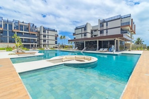 Ein modernes Hotel mit Schwimmbad, Liegestühlen und einem überdachten Bereich.