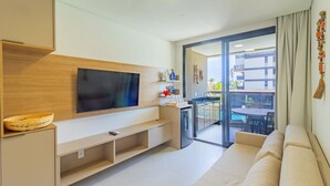 Ein modernes Wohnzimmer mit Flachbildfernseher, Holzschrank, kleinem Kühlschrank und einer Couch.