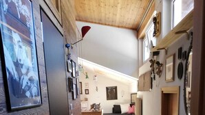 Un pasillo estrecho con paredes de madera y suelo verde, que conduce a una zona de cocina con un lavabo y encimera.