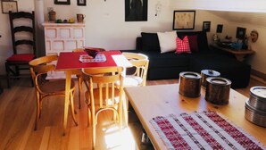 Una sala de estar acogedora con una mesa de comedor, sillas de madera, un sofá negro y un tragaluz.