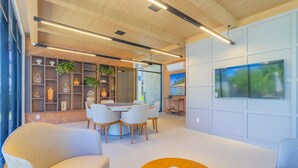 A modern interior with a dining area, seating, and a large TV on the wall. - Cais Eco #304 - Apartment With Pool by Carpediem (Ipojuca)